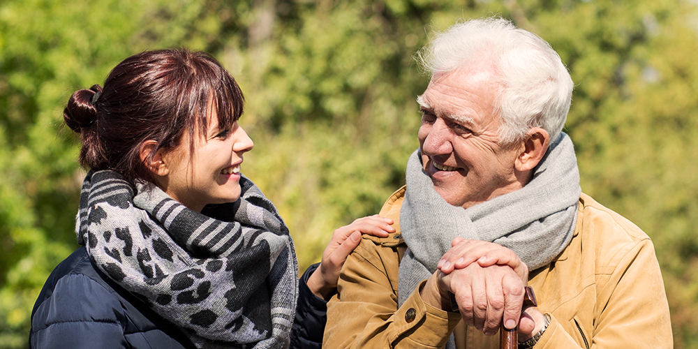 Older man sitting outside with younger woman Older man sitting outside with younger woman
